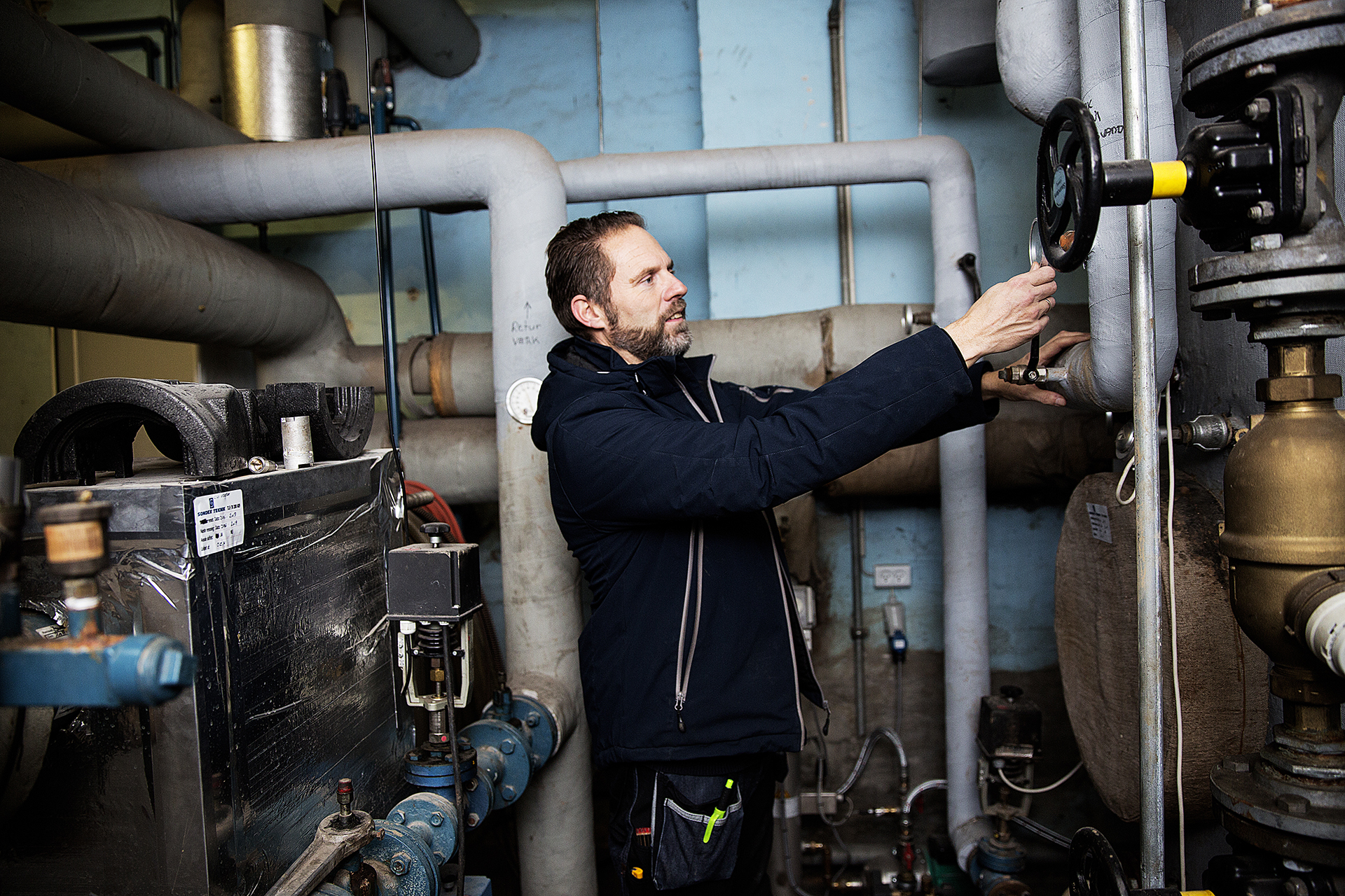 Varmemester fra A/B Elleparken justerer på varmeanlægget